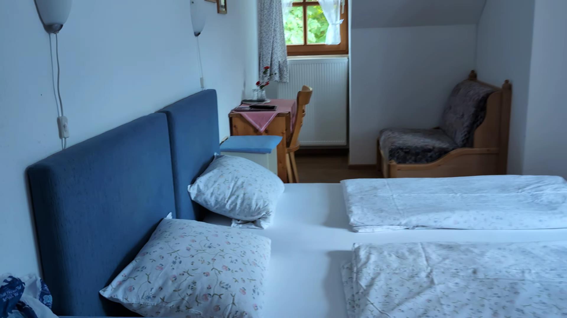 A cozy hotel room in Oberammergau with a king-sized bed, wooden furniture, and a scenic view.