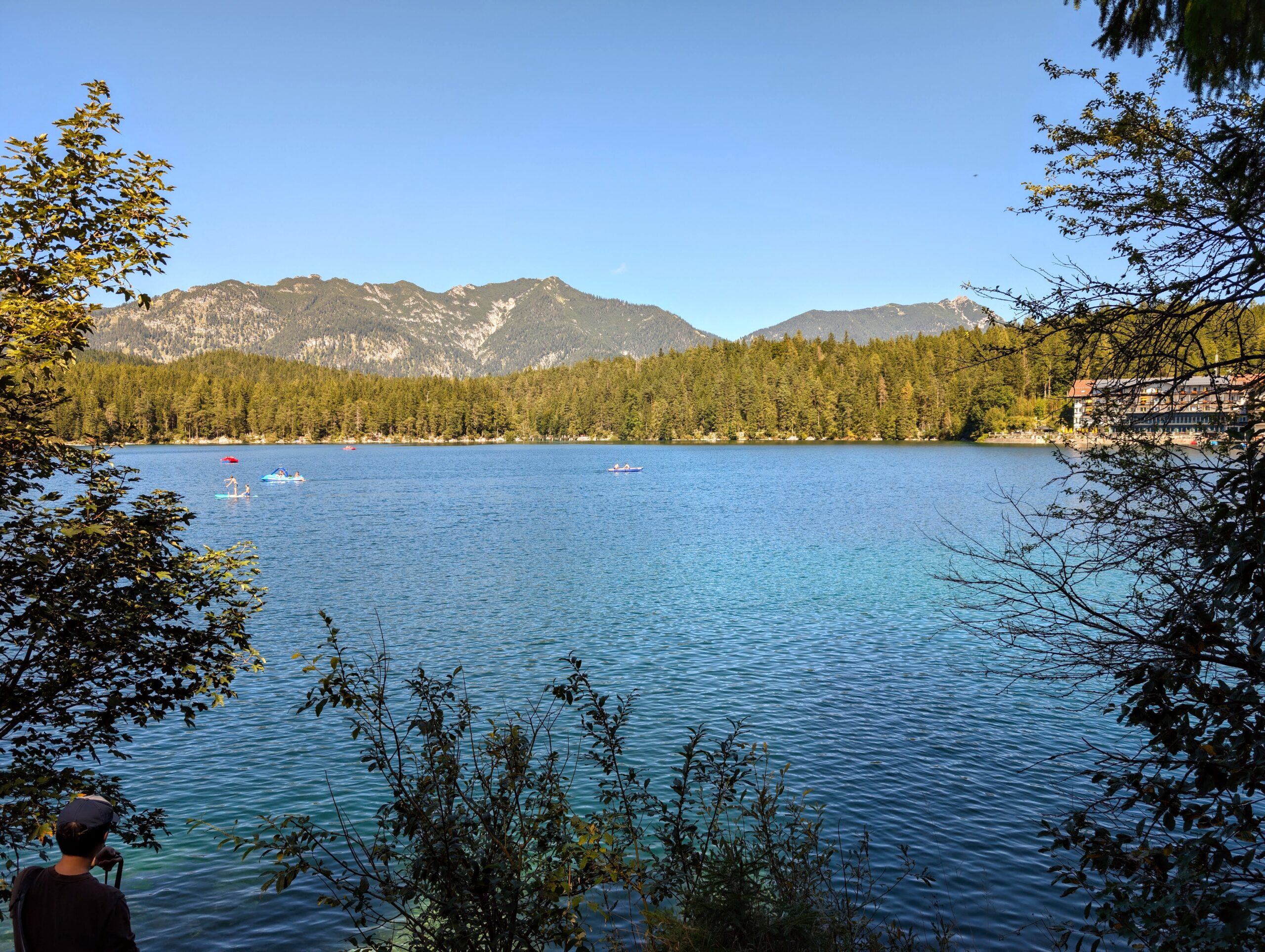 Tranquil view of Eibsee’s clear turquoise waters surrounded by lush forests and towering mountains in the Bavarian Alps.