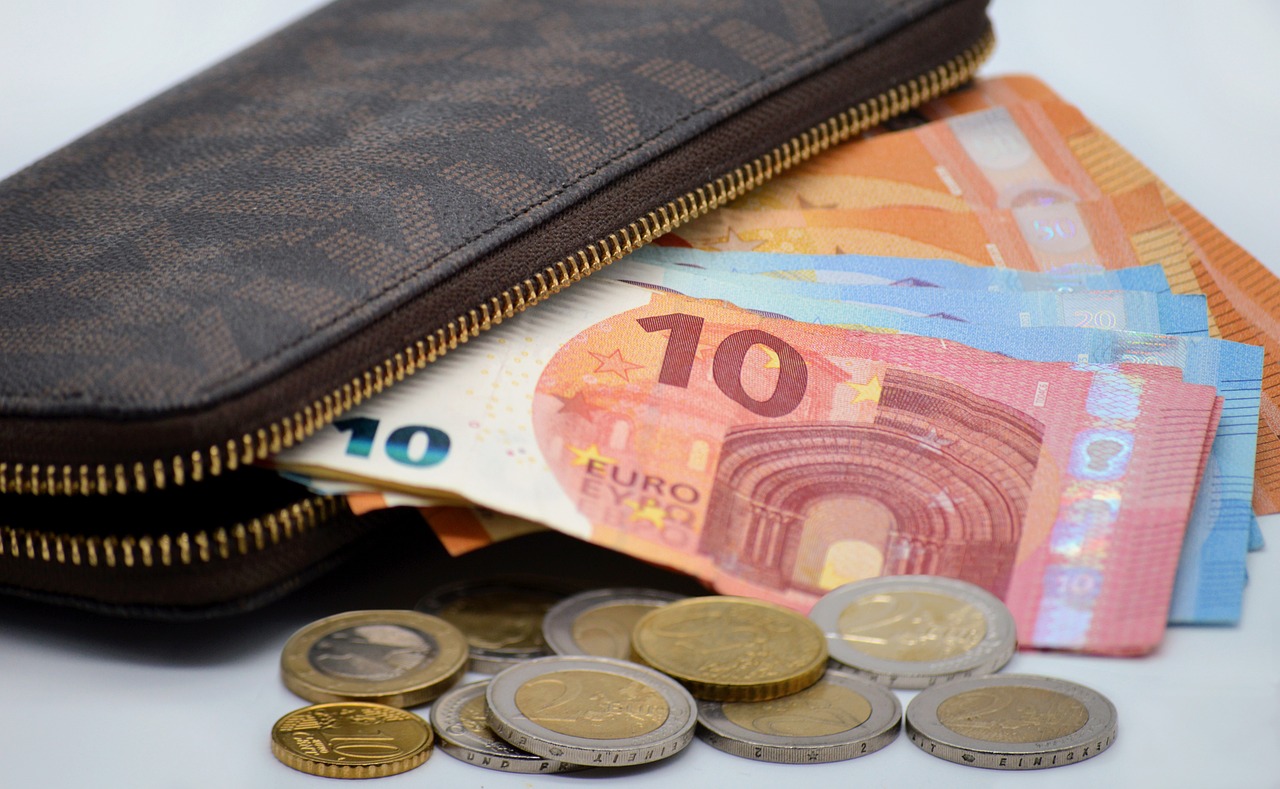 Close-up of currency bills and coins, representing the cost of budgeting for a trip or vacation.